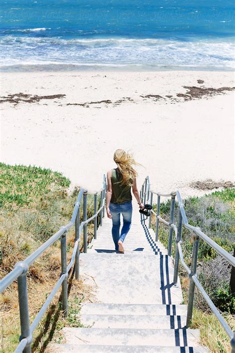 teenage girl walking down a flight of stairs to the beach del colaborador de stocksy jacqui