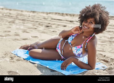 Portrait Of Happy Afro American Woman Lying On Beach With Hand On Neck