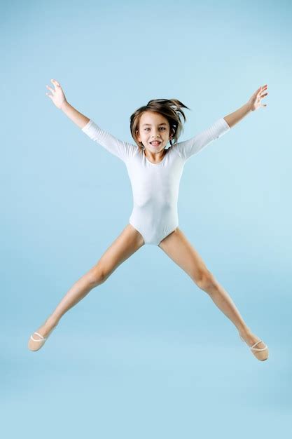 Premium Photo Exhilarated Girl In A White Leotard Jumping In The Air With Legs And Arms Apart