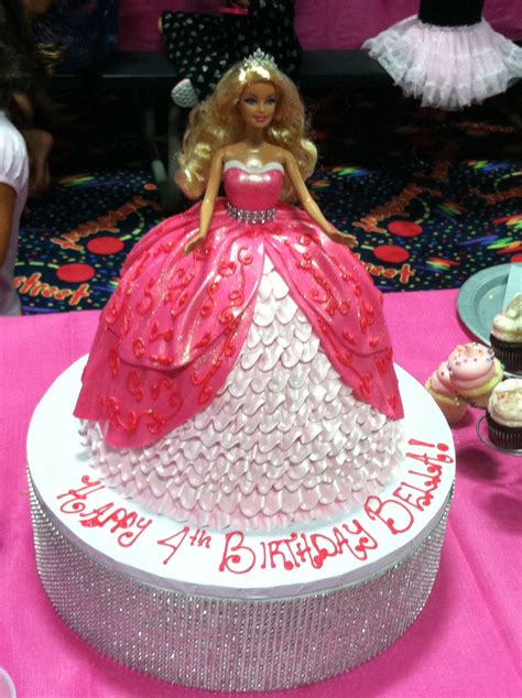 A Barbie Birthday Cake With Cupcakes On The Table In Front Of It