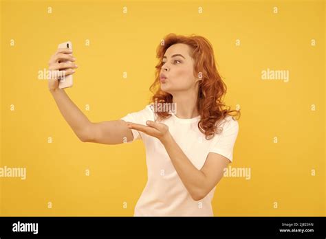 gadget addicted selfie girl blogger yellow background woman give hand kissing to smartphone