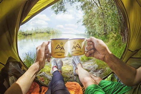 Молодые пары сидя в шатре и выпивая чае пока смотрящ на реке desna Стоковое Фото изображение