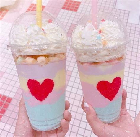 Two People Holding Up Drinks With Strawberries And Marshmallows In Them
