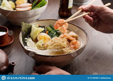Man Eating Asian Ramen With Shrimps And Noodles In A Restaurant Stock