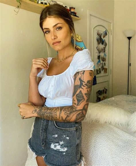 A Woman With Tattoos Standing On A Bed