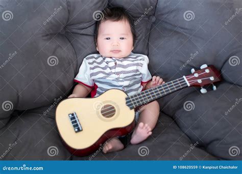 Lovely Baby Sitting On The Soft Sofa With Mini Guitar Babies Musician