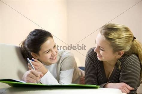 Two Girls Doing Homework Together On The Sofa Download People