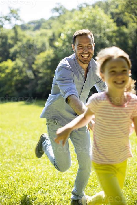 Father Chasing His Little Daughter While Playing In The Park 2879394