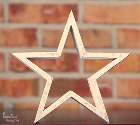 A White Wooden Star Sitting On Top Of A Table Next To A Brick Wall In
