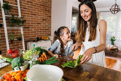 View Mother And Daughter Making Salad In The Kitchen By Stocksy