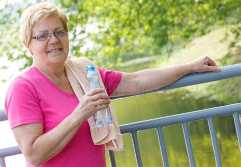 Senior Woman Drinking Water And Resting After Exercise Or Running