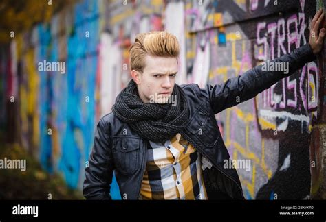 handsome trendy man outdoor in city setting male model wearing black jacket scarf and checked