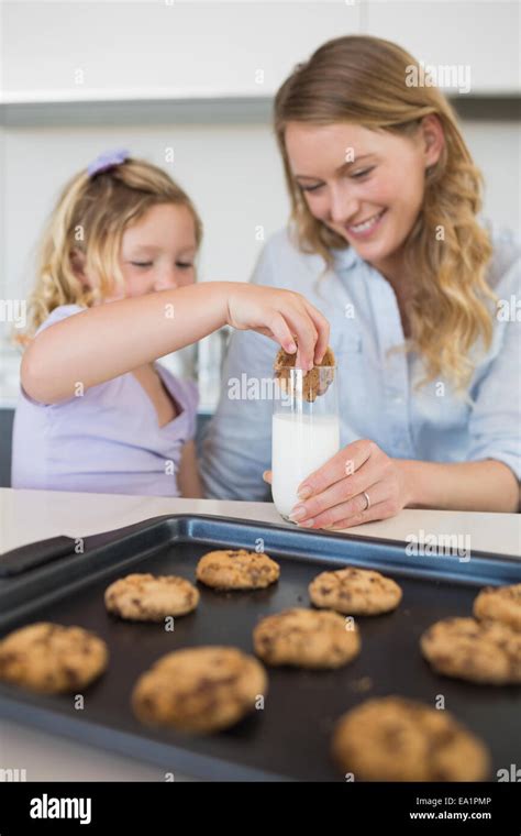 La Madre Con La Hija De Cookie De Inmersión En La Leche Fotografía De