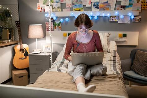 Una Adolescente Seria Con Una Laptop De Rodillas Sentada En La Cama