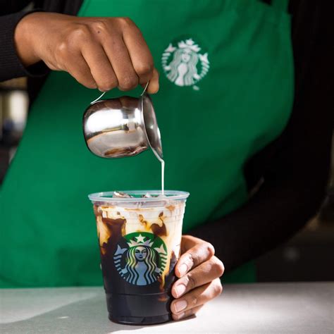 A Person Pouring Coffee Into A Starbucks Cup