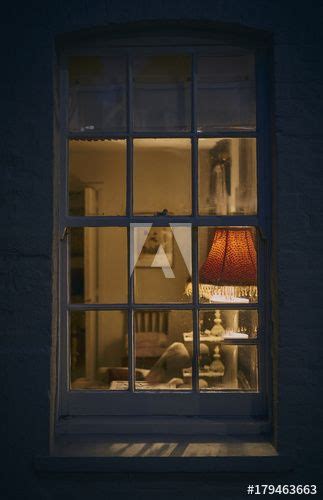Looking Through A Window At Night From Outside Into A Rustic Cottage