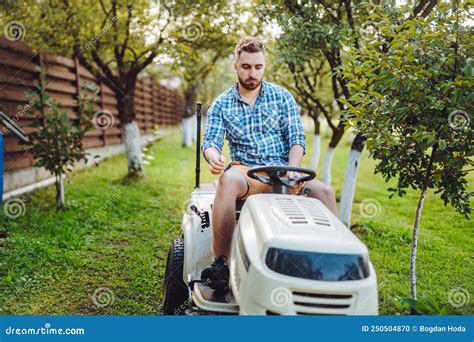 Gardener Worker Using Lawn Tractor And Cutting Grass Through Garden