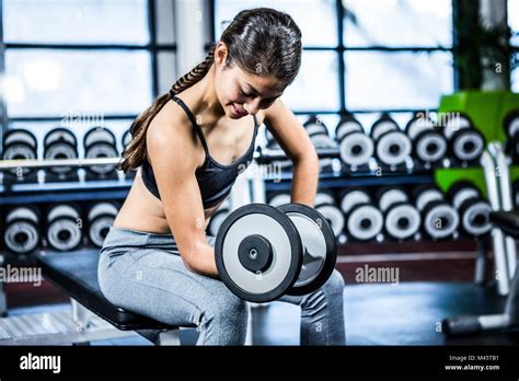 Muscular Woman Lifting Dumbbell While Sitting On Bench Stock Photo Alamy