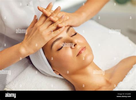Cosmetologist Making Facial Massage Or Treatment For Young Womans Face In Beauty Spa Salon Stock