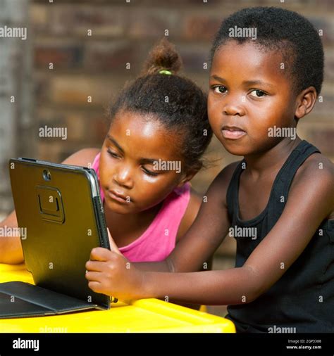 Close Up Of Two African Kids Doing Homework On Tablet Outdoors Stock