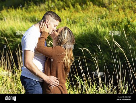 Husband And Wife Spending Quality Time Together And Kissing Outdoors Near A Stream In A City