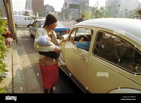 An Indian Woman Begs At A Busy Intersection While Carrying Her Child In