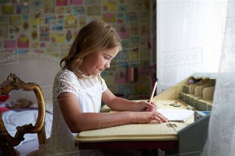 Young Girl Sitting At Desk And Writing In Bedroom Stock Photo Dissolve