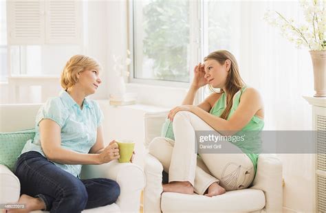 Mother And Adult Daughter Sitting On Sofa And Talking High Res Stock