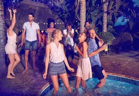 Friends Hanging Out At Summer Poolside Party At Night Stock Image