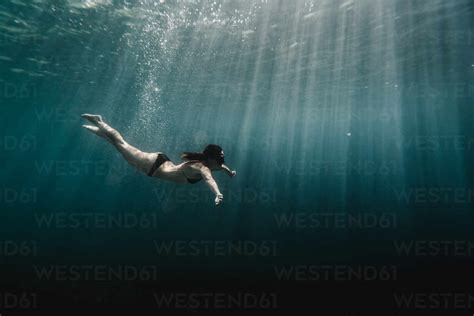 Full Length Of Woman Swimming Underwater In The Ocean Stock Photo