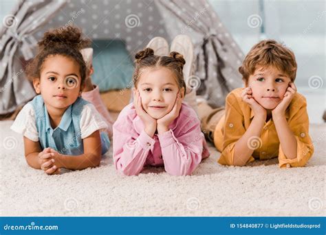 Beautiful Multiethnic Children Lying On Carpet And Looking Stock Image