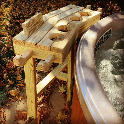 a wooden bench next to a hot tub in the fall leaves with water running