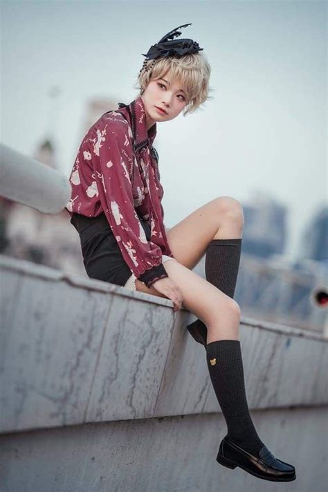A Woman Sitting On Top Of A Cement Wall Wearing Knee High Socks And Black Boots