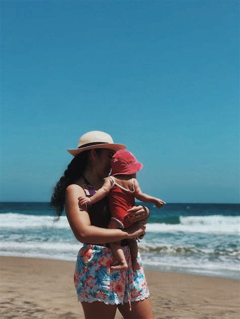 Mother Holding Her Baby In Front Of Seashore During Daytime · Free