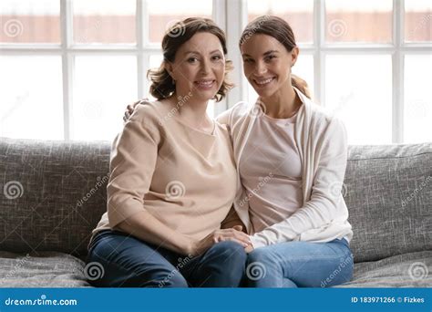 Portrait Of Happy Mature Mom And Adult Daughter On Couch Stock Photo