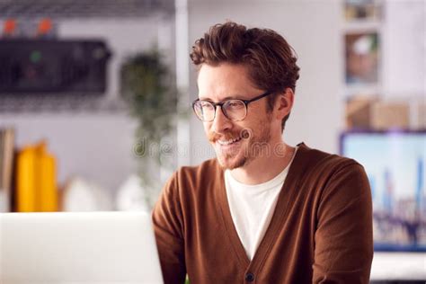 Male Architect Sitting At Desk In Office Working On Laptop Stock Photo