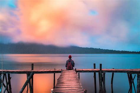 Man Sitting On A Dock By The Lake At Sunset Sky By Alexander Grabchilev