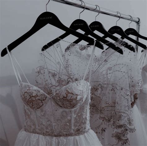 Three Dresses Are Hanging On A Rack In Front Of A Wall With Clothes Hangers