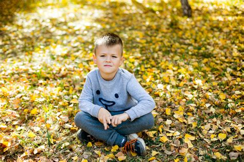 Portrait Of A Cute 5 6 Years Old Boy Sitting On The Ground Covered With