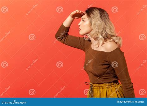 Woman Holding Hand Above Eyes And Looking Far Away Side View Stock