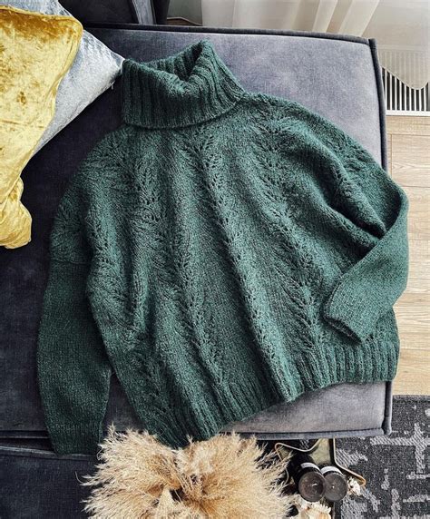 A Teddy Bear Laying On Top Of A Chair Next To A Green Knitted Sweater