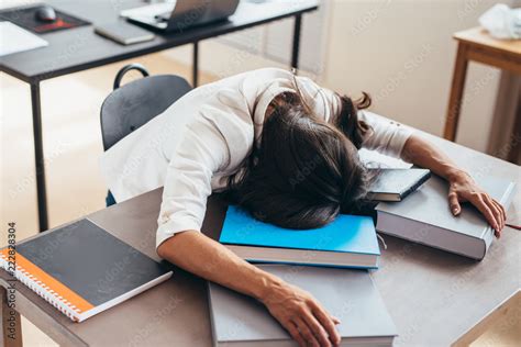 Tired Female Student Sleeping On Desk Face And Hands On Books 素材庫相片
