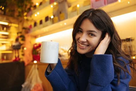 Smiling Young Caucasian Female Looking At Camera Holds Cup Of Latte