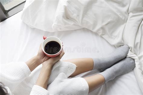 Relaxing Young Woman Enjoying Her Coffee While Sitting In Bed Stock