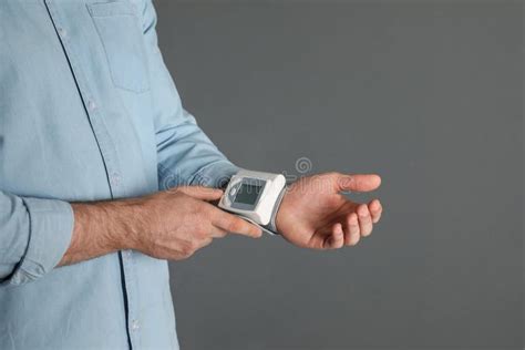 Young Man Checking Pulse With Digital Medical Device On Grey Background