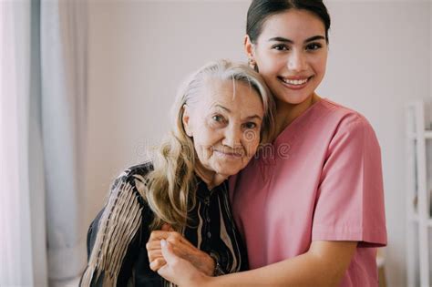 Happy Caregiver And Senior Patient Smiling And Looking At Camera Stock
