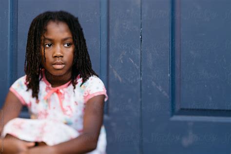 african american girl sitting in front of a blue door by stocksy contributor gabi bucataru