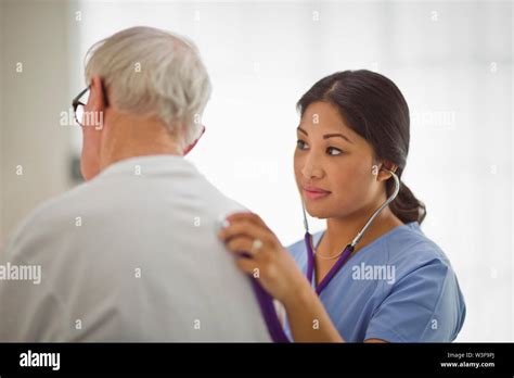 Female Nurse Listening To The Heart Beat Of An Elderly Male Patient