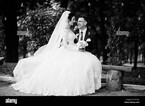 newly married couple sitting in the park on the sunny summer wedding day black and white photo