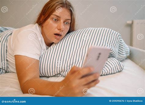 Shocked Young Woman Laying In Bed And Looking At Alarm At Smartphone In